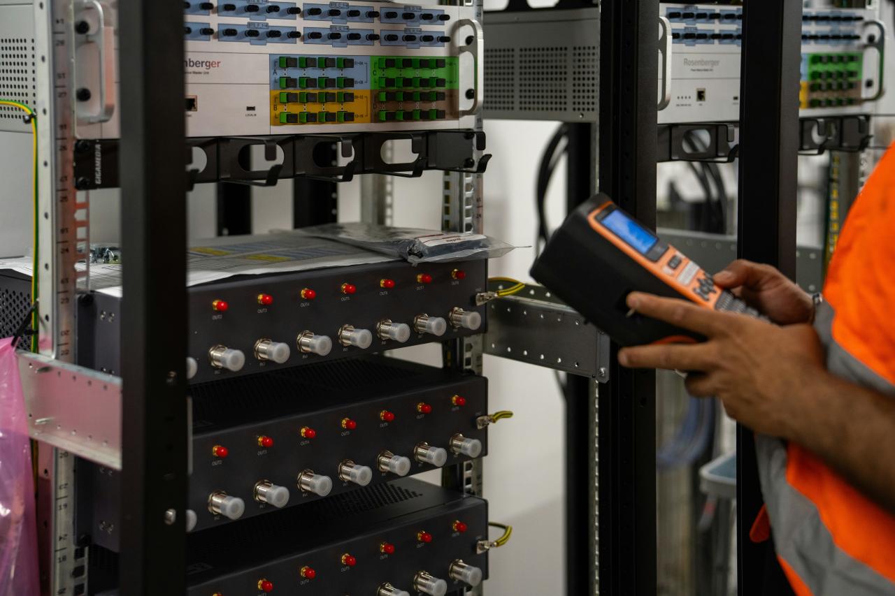 Technician inspecting server racks with a handheld diagnostic tool