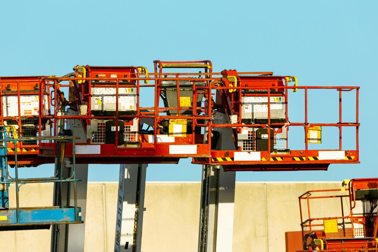 Red aerial work platforms with metal railings against a clear blue sky